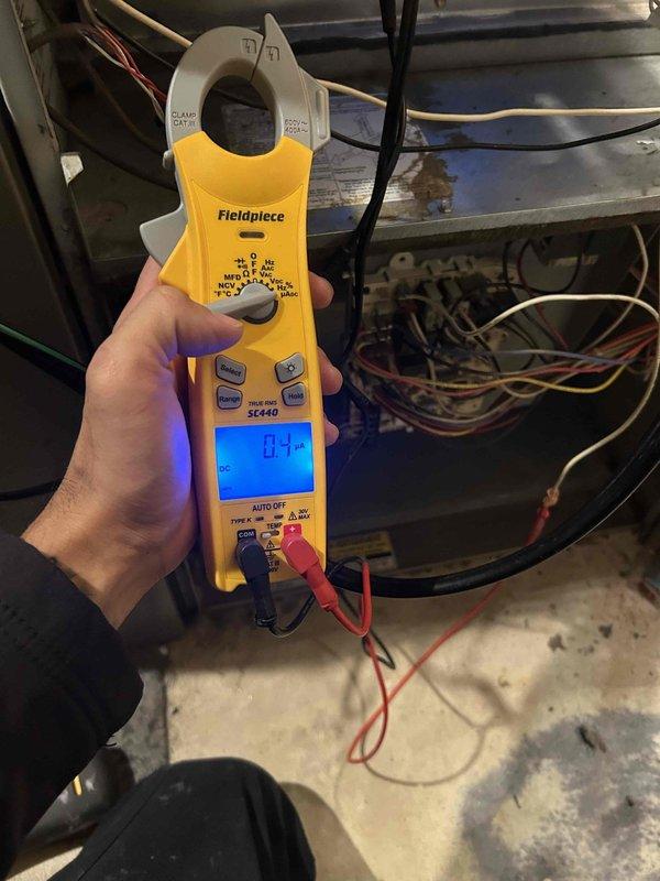 Completed membership maintenance inspection on residential HVAC system located in basement utility area. Performed comprehensive air conditioning tune-up including visual inspection of furnace unit, ductwork, and associated components. Verified gas line connections, shutoff valve operation, and proper installation of flexible gas connector. Inspected electrical connections, wiring, and control systems using Fieldpiece SC440 clamp meter to verify amperage readings and confirm system operating within normal parameters. Checked air filter condition and return air pathways for proper airflow. Documented equipment condition through photographic records showing furnace unit, plenum assembly, copper and PVC piping, and overall system configuration for maintenance history records.