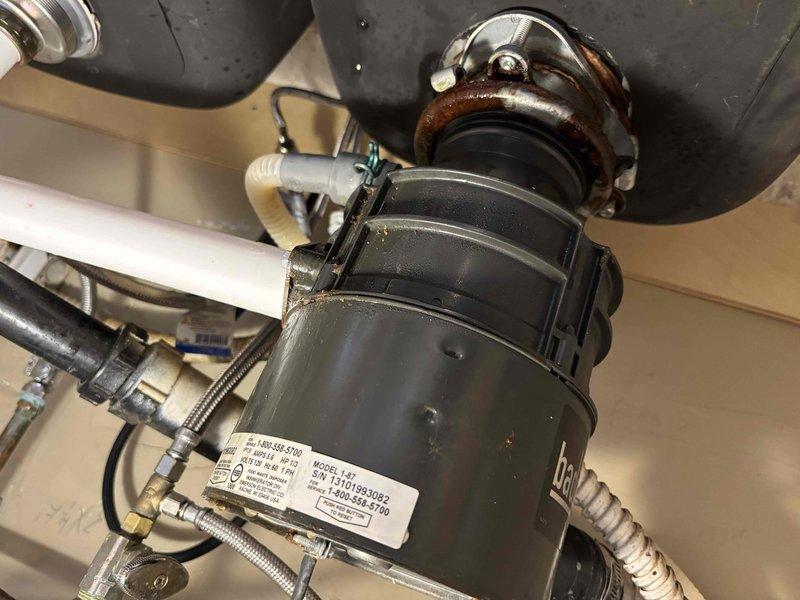 Responded to service call for malfunctioning and leaking garbage disposal in kitchen. Upon inspection, assessed the existing disposal unit and associated plumbing connections, including mounting assembly, discharge piping, and water supply lines. Evaluated the condition of the disposal, P-trap configuration, and drain connections to determine appropriate repair or replacement solution. Documented existing installation showing signs of age and wear on mounting hardware and connections.