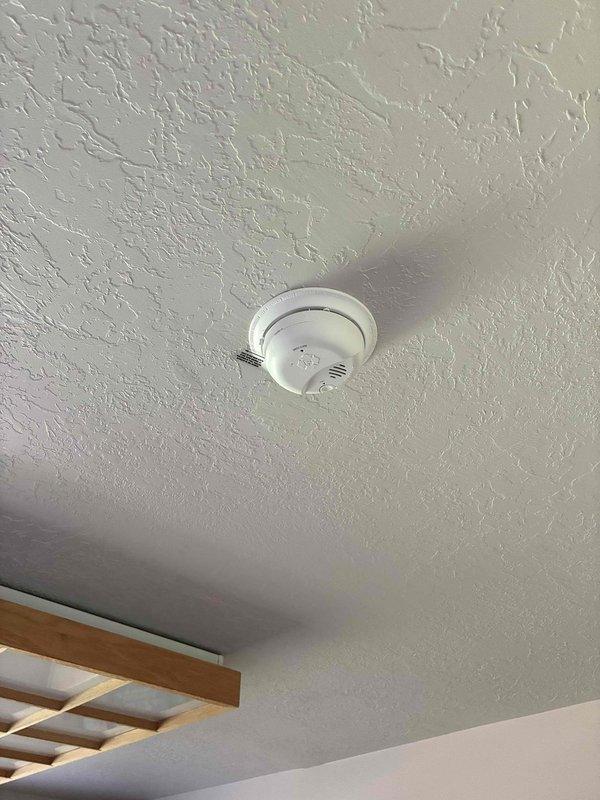 Responded to report of intermittent burning odor and smoke alarm activation in upstairs hallway. Conducted comprehensive inspection of all smoke detectors on upper level and evaluated electrical panel for potential issues. Found evidence of dust accumulation and discoloration around multiple smoke detector units, consistent with age-related degradation in 31-33 year old residence. Replaced all aging smoke detectors throughout upper level, including units in hallway near bedrooms and shower area, with new interconnected photoelectric/ionization combination units meeting current code requirements. Verified proper electrical connections, tested alarm functionality and interconnection between all new units, and confirmed no underlying electrical panel concerns or wiring issues contributing to false alarms or odors.