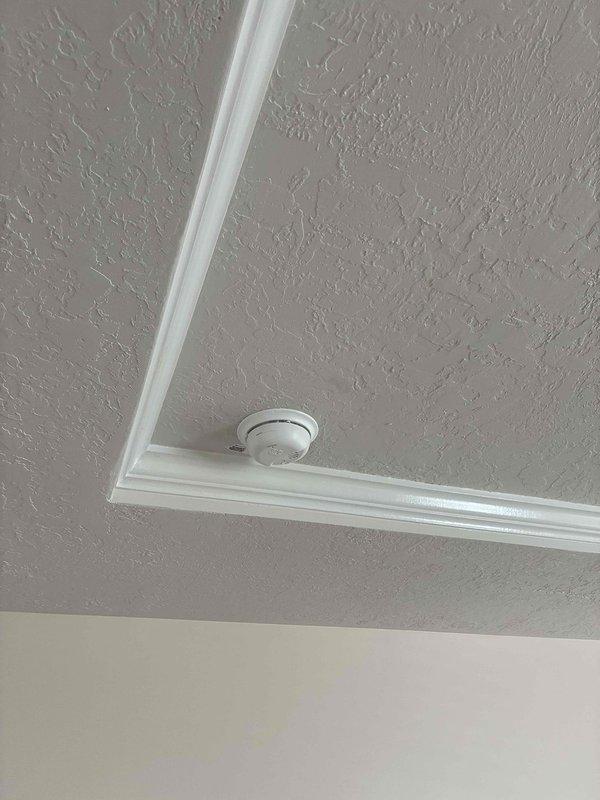 Responded to report of intermittent burning odor and smoke alarm activation in upstairs hallway. Conducted comprehensive inspection of all smoke detectors on upper level and evaluated electrical panel for potential issues. Found evidence of dust accumulation and discoloration around multiple smoke detector units, consistent with age-related degradation in 31-33 year old residence. Replaced all aging smoke detectors throughout upper level, including units in hallway near bedrooms and shower area, with new interconnected photoelectric/ionization combination units meeting current code requirements. Verified proper electrical connections, tested alarm functionality and interconnection between all new units, and confirmed no underlying electrical panel concerns or wiring issues contributing to false alarms or odors.