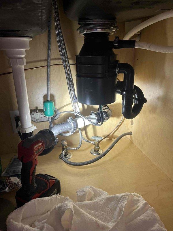 Responded to downstairs kitchen sink backup that had persisted for approximately one week. Upon arrival, confirmed water was draining normally from main kitchen sink but backing up into lower level kitchen sink. Inspected under-sink plumbing and recently installed garbage disposal unit. Performed professional cable snaking of the affected drain line to clear blockage causing the backup condition. Verified proper drainage flow restored to downstairs kitchen sink upon completion of rooting service.