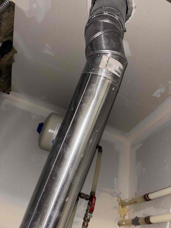 Performed water heater flush service on a 6-year-old State brand tank-type water heater located in the utility room accessible through the garage. Inspected all plumbing connections, including copper supply lines, PVC drainage piping, and flue venting system, confirming proper installation and operation of water heater alongside adjacent water treatment system with functioning valve assemblies.