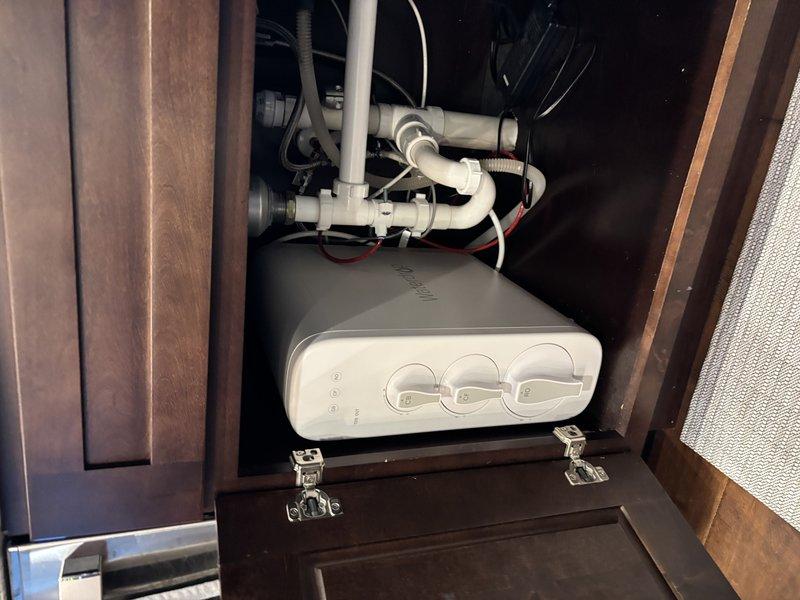 Replaced water pressure regulator valve and verified system pressure reading at 150 PSI using calibrated PASCO gauge. Installed customer-provided under-sink water filtration unit in kitchen cabinet with complete plumbing integration, including PVC pipe connections, supply line hookups, and drain line configuration. Tested all connections for leaks and confirmed proper operation of filtration system controls.