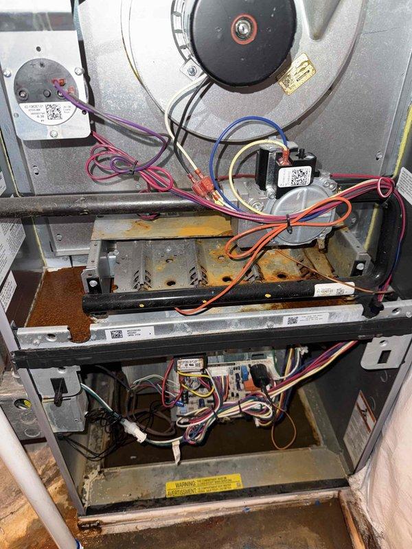 Completed Green Shield heating maintenance on single-system furnace unit located in closet. Performed comprehensive inspection of blower motor assembly, heat exchanger, burner components, and control board. Investigated reported water leak issue, inspected condensate system and heat exchanger for potential breach points. Verified all electrical connections, safety controls, and ignition components functioning properly. Documented temperature differential reading of 13.3 degrees across system. Noted minor surface corrosion on heat exchanger panels and general dust accumulation consistent with 5-9 year old unit. All wiring connections secure with proper color-coded routing throughout furnace compartments. Unit operational at time of service completion.