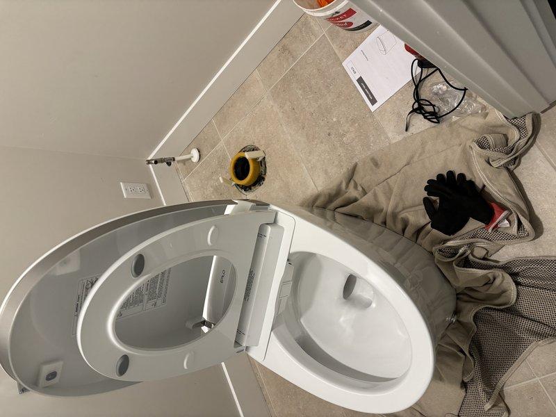 Completed toilet replacement in residential bathroom. Removed existing toilet fixture and installed new modern dual-flush toilet with chrome flush lever and digital display feature. Secured unit to floor flange, connected water supply line, and tested flush mechanism for proper operation. Verified all seals for leaks and confirmed stable mounting. Left work area clean with new fixture fully operational.