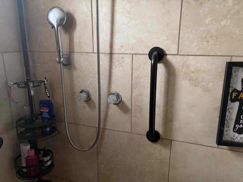 Responded to reported shower leak in main bathroom. Upon inspection, accessed plumbing behind wall to identify source of water leakage. Examined shower valve assembly, supply lines, and connections. Repaired/replaced faulty components causing the leak. Verified proper operation of shower controls and handheld showerhead system. Tested all connections for leaks and confirmed repair resolved the issue.