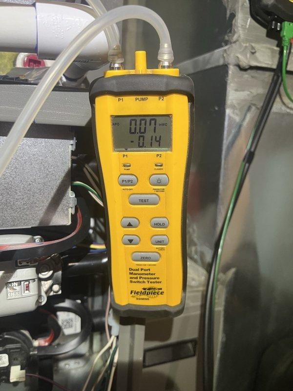 Responded to second opinion request for 5-6 year old furnace in basement with concerns about improper sealing and potential gas leakage reported by another contractor. Performed comprehensive inspection of furnace unit, measuring electrical amperage at 2.2 amps AC using clamp meter and conducting pressure diagnostics with dual port manometer showing -8.14 inWG. Evaluated combustion chamber sealing, flue connections, and gas line integrity to assess rust and leakage concerns, providing professional assessment of unit condition and safety status.