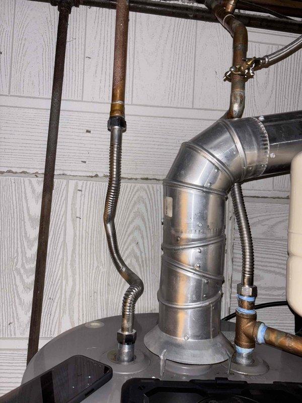 Performed membership plumbing inspection and water heater flush on 4-year-old tank-style unit located in basement. Inspected pressure relief valve assembly with gauge reading at zero PSI, verified brass fittings and connections for proper operation. Completed routine water heater maintenance including sediment flush, examined all copper piping connections and flexible supply lines for leaks or deterioration, and confirmed proper venting through galvanized ductwork elbow assembly.