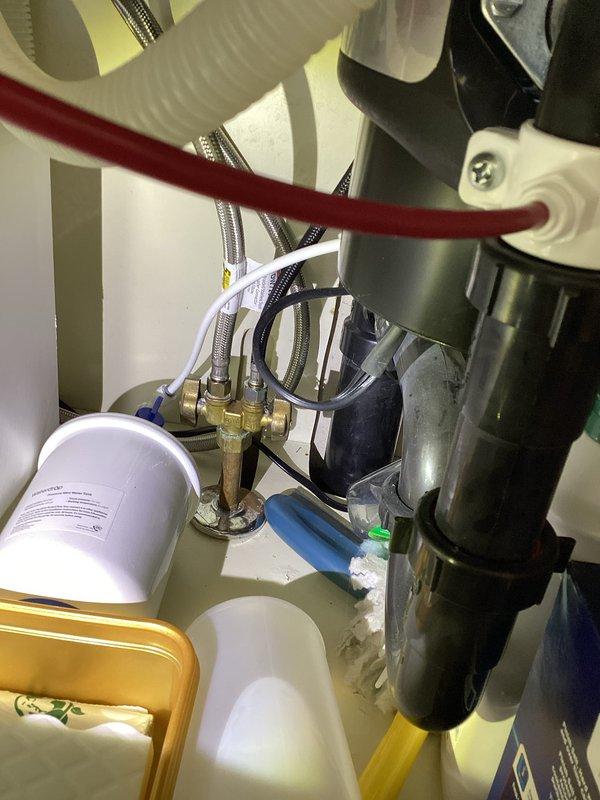 Completed comprehensive plumbing membership inspection of residential water supply system and fixtures. Documented condition of bathroom sink showing accumulation of sediment and mineral deposits around drain area requiring routine cleaning maintenance. Inspected mechanical room plumbing infrastructure including water heater connections, multiple supply lines with braided stainless steel flex hoses, brass fittings, shut-off valves, and what appears to be water filtration or expansion tank equipment, confirming all connections are secure and system components are properly installed.
