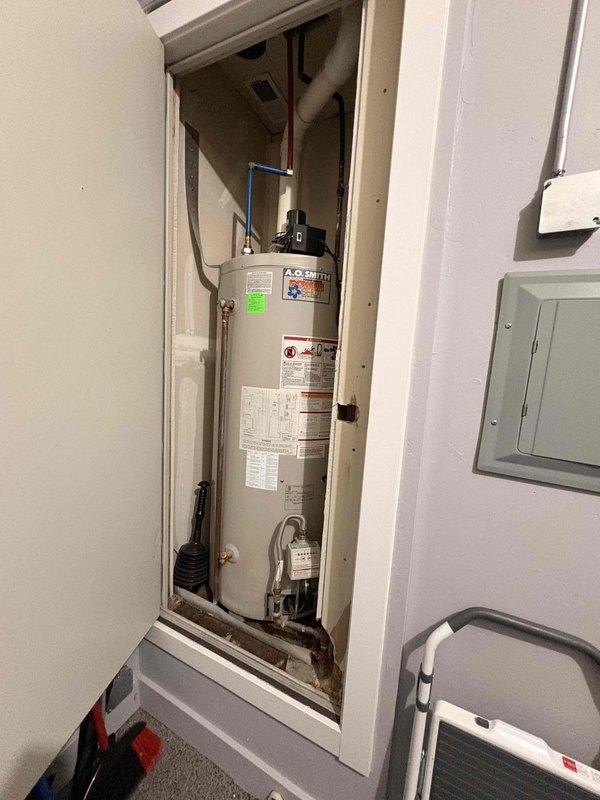 Responded to reported intermittent leak from top fixtures and drip pan of 20-year-old A.O. Smith tank-style water heater in garage utility closet causing water damage to adjacent property. Inspected unit and all connections including top-mounted brass fittings, PEX supply lines, and drip pan assembly. Evaluated overall condition of aging water heater and provided assessment for leak repair versus full unit replacement due to age and extent of water intrusion.