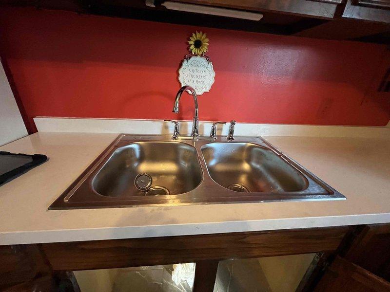Reconnected kitchen double-basin stainless steel sink and supply lines following countertop replacement. Verified all hot and cold water connections were secure, tested shut-off valves for proper operation, and confirmed no leaks at supply line connections or drain assembly. System restored to full functionality with all fixtures operating properly.