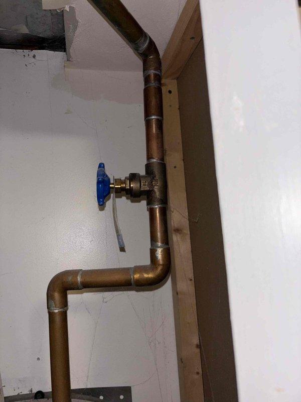 Responded to service call for non-functioning tank-style water heater over 6 years old located in garage area. Performed comprehensive assessment of existing water heater system and surrounding plumbing infrastructure, including examination of copper supply lines, shut-off valves, and connection points. Inspected plumbing configuration featuring vertical and horizontal copper pipe runs with blue-handled shut-off valve, noting aged copper with typical oxidation and patina. Evaluated installation accessibility through garage entry point and assessed crawl space area containing HVAC ductwork and structural components that may impact removal and replacement procedures. Documented existing plumbing connections, pipe sizing, and current water heater specifications. Provided detailed estimate options for tank water heater replacement, including various tank size capacities suitable for household demand, complete installation labor, removal and proper disposal of existing failed unit, and all 