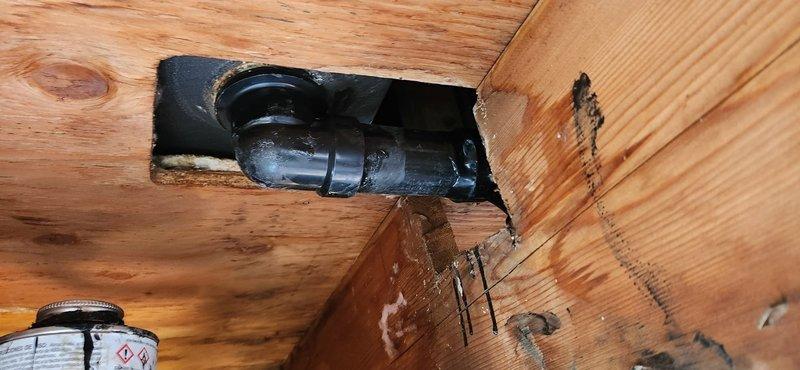 Installed new waste and overflow assembly using closed access method, tying into existing drainage system with no-hub band connections. Completed drywall repair and restoration work to access area, returning wall surfaces to finished condition.