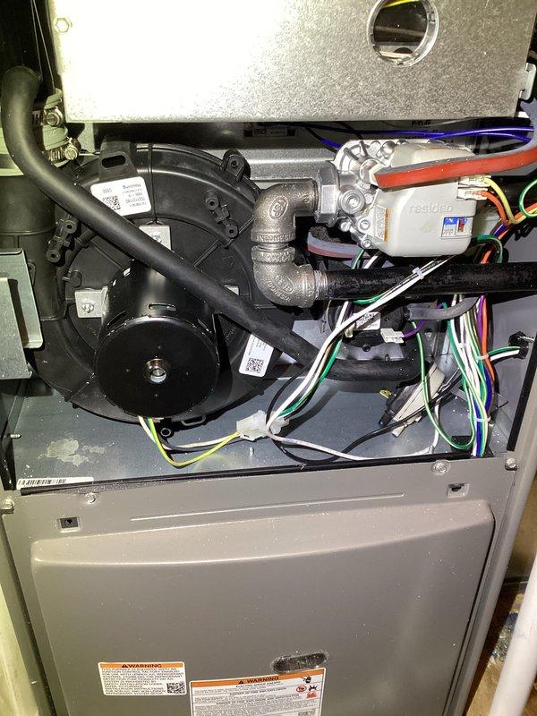 Completed Priority Plus maintenance service on a 2-year-old HVAC system located in garage utility closet. Addressed customer concern regarding air conditioning unit running for 1.5-2 minutes before cutting off to delay mode, then resuming normal operation. Performed comprehensive cooling system maintenance including inspection of outdoor condenser unit, refrigerant charge verification, electrical connections, and operational testing of short-cycling issue. Conducted furnace tune-up including inspection and cleaning of blower wheel assembly, examination of gas valve and burner assembly, verification of all electrical connections and control modules, inspection of heat exchanger, and testing of all safety controls. Documented internal components with photographs showing clean blower wheel with intact blades and proper shaft alignment, as well as complete furnace cabinet interior displaying blower motor assembly, gas valve connections, control board, and properly routed wiring harnesses. 