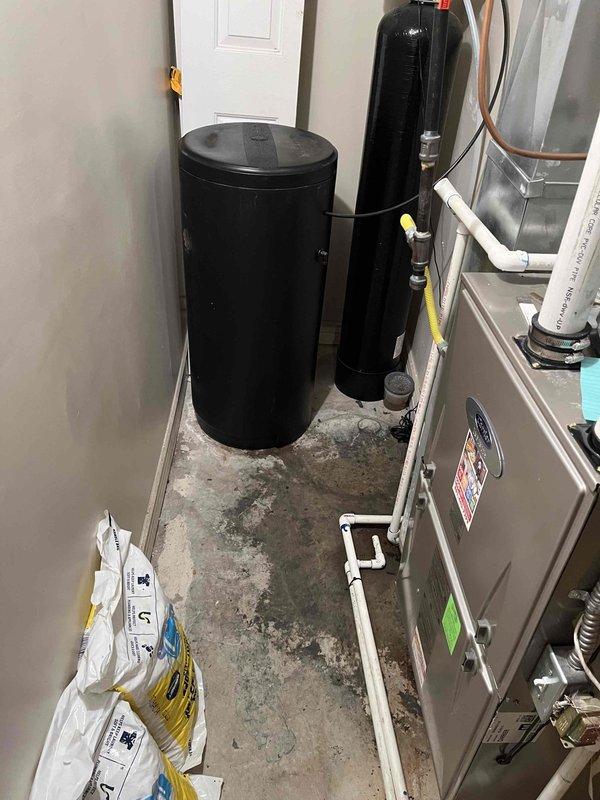 Responded to utility room drain backing up when washing machine discharged. Upon arrival, inspected laundry area and utility room containing water softener system and HVAC equipment. Located floor drain in utility room experiencing backup issues during washer drain cycles. Performed diagnostic inspection to identify cause of drainage obstruction and water leakage through drain fixture.