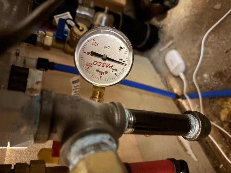 Responded to emergency call for smart water valve leak detection and automatic shutoff. Upon arrival, inspected basement plumbing system and located dampness on pipe near valve installation point. Conducted thorough diagnostic evaluation to determine if moisture was from active leak or condensation buildup. Monitored pressure gauge readings on plumbing system and inspected all accessible pipe connections and fittings. Examined bathroom plumbing including drain assembly and wall cavity access point to assess overall system condition. Verified no active dripping or pooling water present at valve location or surrounding areas. Determined moisture was likely condensation-related rather than active leak, explained findings to homeowner, and provided recommendations for monitoring. Reset smart water valve system and restored water supply to residence.