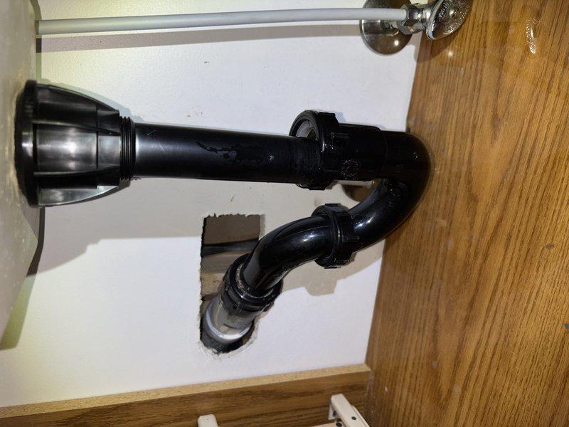 Responded to emergency call for smart water valve leak detection and automatic shutoff. Upon arrival, inspected basement plumbing system and located dampness on pipe near valve installation point. Conducted thorough diagnostic evaluation to determine if moisture was from active leak or condensation buildup. Monitored pressure gauge readings on plumbing system and inspected all accessible pipe connections and fittings. Examined bathroom plumbing including drain assembly and wall cavity access point to assess overall system condition. Verified no active dripping or pooling water present at valve location or surrounding areas. Determined moisture was likely condensation-related rather than active leak, explained findings to homeowner, and provided recommendations for monitoring. Reset smart water valve system and restored water supply to residence.