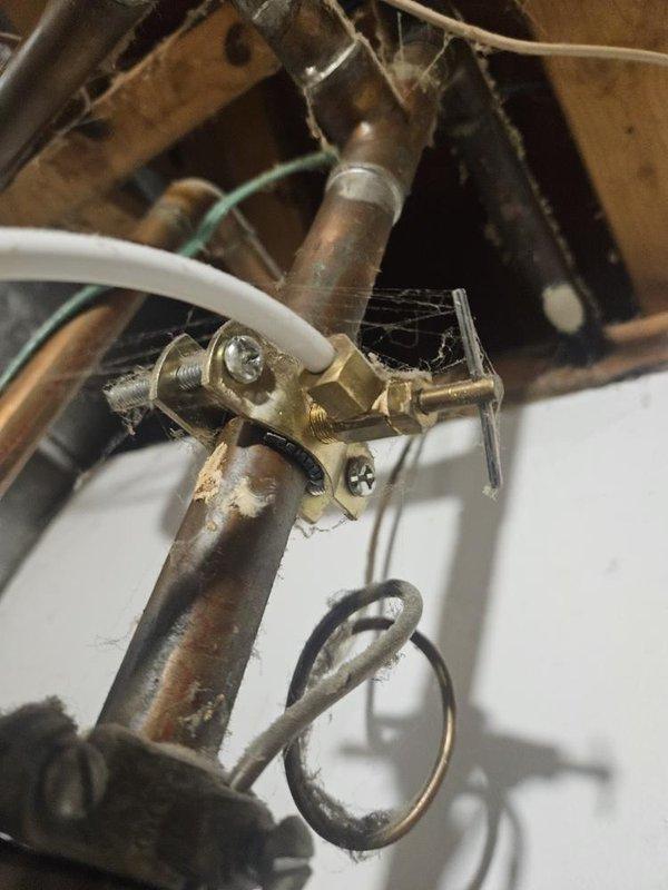 Responded to service call for moisture accumulation at base of 16-year-old residential tank-style water heater located in basement. Upon inspection, identified significant corrosion and oxidation on copper supply piping and brass valve assembly, with visible green patina indicating extended exposure to moisture. Observed deteriorated plumbing connections with evidence of slow leaking at tank base and pressure relief valve discharge piping. Water heater showed advanced age-related degradation with corroded fittings and compromised integrity of tank bottom. Documented condition of existing plumbing infrastructure including pressure regulator valves, supply lines, and mounting hardware. Assessed water damage to surrounding wall surfaces and floor area beneath unit. Provided comprehensive evaluation of water heater system and recommended full tank replacement due to age of equipment exceeding typical service life and active leak condition presenting risk of catastrophic failure.