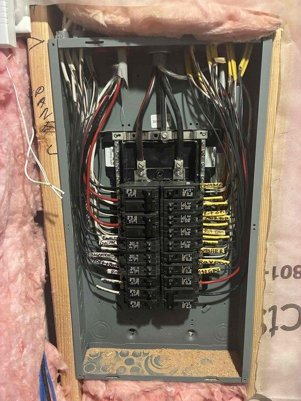 Performed an electrical maintenance inspection of the main service panel with the cover removed, visually checking the breakers, conductors, main lugs, and circuit labeling. Observed organized branch circuit wiring with labeled conductors and noted wood shavings debris at the bottom of the panel enclosure. Verified the combination smoke/carbon monoxide alarm mounted to the framing was in place and free of visible damage, corrosion, or defects, with no other deficiencies identified.