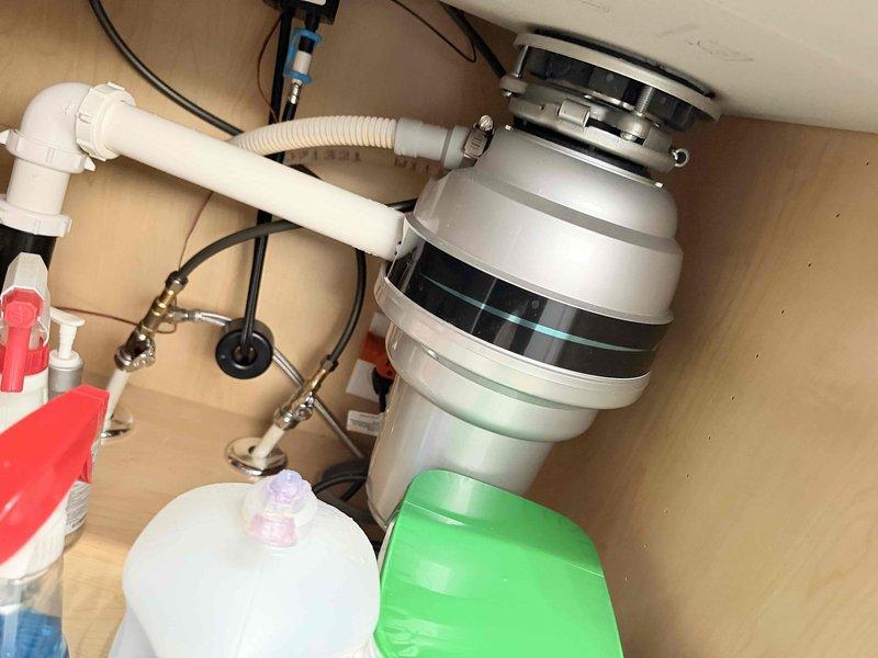 Performed a plumbing member inspection of the kitchen fixtures and under-sink components. Inspected the garbage disposal, including the mounting flange, slip-joint drain fittings, flexible discharge hose with clamp, and electrical connection, along with the brass shutoff valves and braided supply lines, and found no leaks, corrosion, or damage. Evaluated the pull-down kitchen faucet and sink drain, which were in good condition with no deficiencies noted.