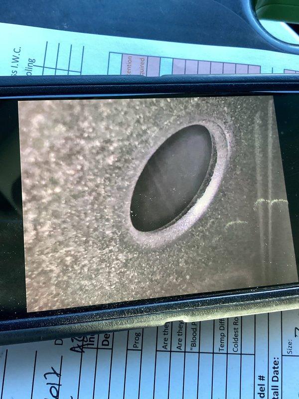 Performed a comprehensive tune-up on a 10-year-old basement furnace, including inspection of the blower assembly, which showed light dust and debris accumulation on the blower wheel blades and housing. Inspected the secondary heat exchanger/condensate drain port and found heavy crystalline mineral and scale buildup around the rim of the opening, indicating restricted drainage. Verified system operation and recorded performance readings including temperature differential and static pressure.
