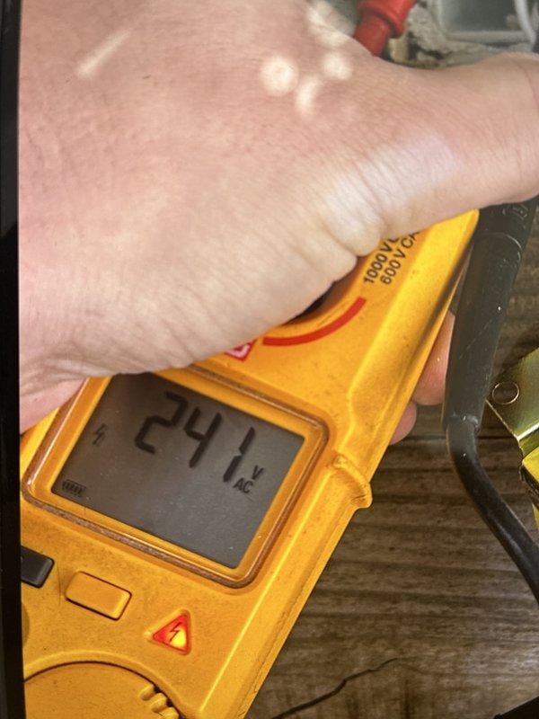 Troubleshot a non-functioning front doorbell and verified 241 V AC at the receptacle terminals with a clamp meter and tester, confirming line voltage was present at the box and the fault was not a loss of supply. Removed the cover plate and inspected the wiring in the recessed metal box to evaluate the doorbell transformer circuit.