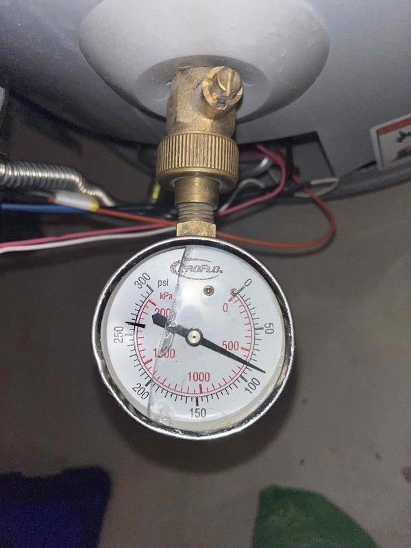Diagnosed a 7-year-old A.O. Smith 50-gallon tanked water heater producing only lukewarm water; the status light flashed a six-blink fault code that indicates burner assembly replacement. During inspection, found a cracked-lens ProFlo pressure gauge threaded onto a brass fitting at the base of the tank, reading approximately 100 psi, and noted a worn, chipped valve stem on the fitting. Documented the findings and presented repair options, including burner assembly replacement, to restore full hot water output.