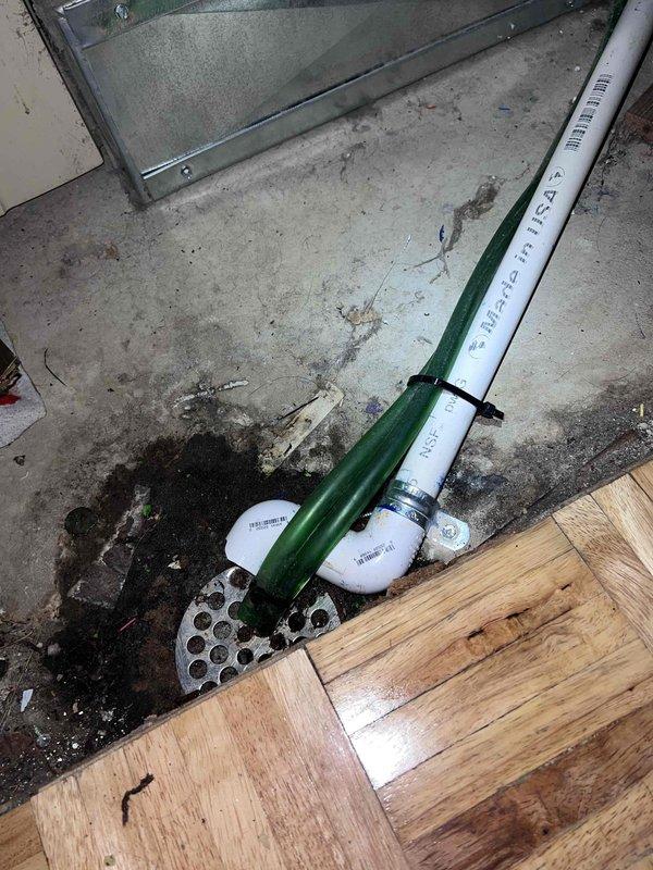Performed warranty recall to correct failed inspection items on the AC installation. Secured the condensate drain line and flexible hose at the floor drain with a zip tie and clamp so the line remains properly terminated at the drain, and verified the flexible conduit (AC whip) is secured to the disconnect within the 8-inch maximum. Confirmed the condenser, refrigerant lines, and electrical connections are in good condition with no visible damage, and documented the corrected work with photos.