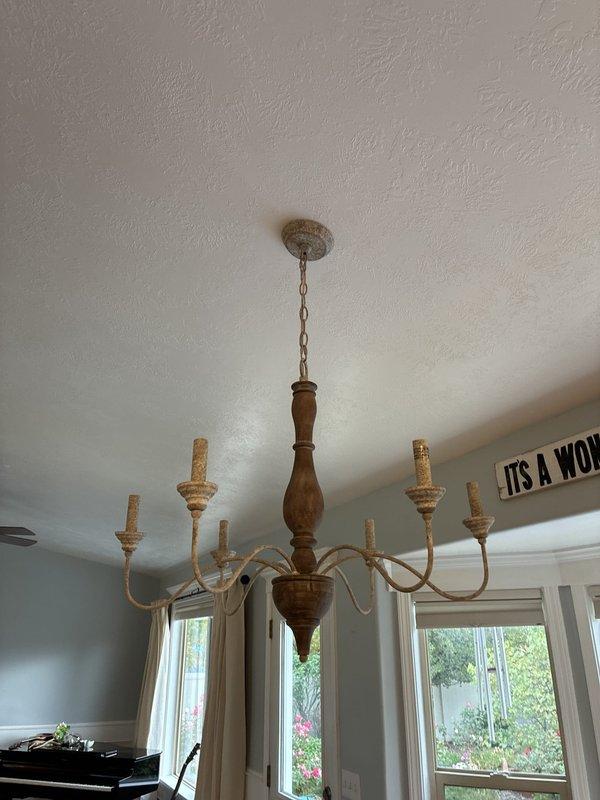 Removed existing light fixtures over the kitchen island and dining table and installed three new pendant lights with dark bronze canopies and fabric shades above the island, along with a new chandelier over the kitchen table. Made all electrical connections, secured the fixtures to the ceiling boxes at staggered pendant heights, and tested for proper operation. The new fixtures function correctly, and the existing recessed LED lighting was left undisturbed.
