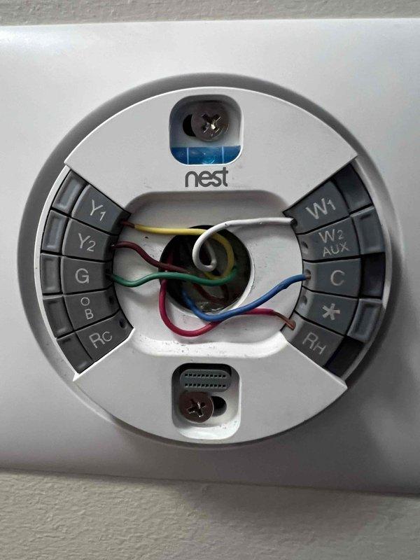 Responded to callback for reported heating operation when thermostat was set to 73–76°F. Inspected Nest thermostat base plate and verified wiring terminations at Y1, Y2, G, W1, C, and Rh, noting unterminated R and W conductors tucked in the wall cavity. Observed the thermostat displaying "COOL STAGE 2" and used a handheld inspection probe to check the wall surface for anomalies, finding no damage, frost, or rust. Documented wiring configuration and thermostat operating status for team review and coordination of next steps.