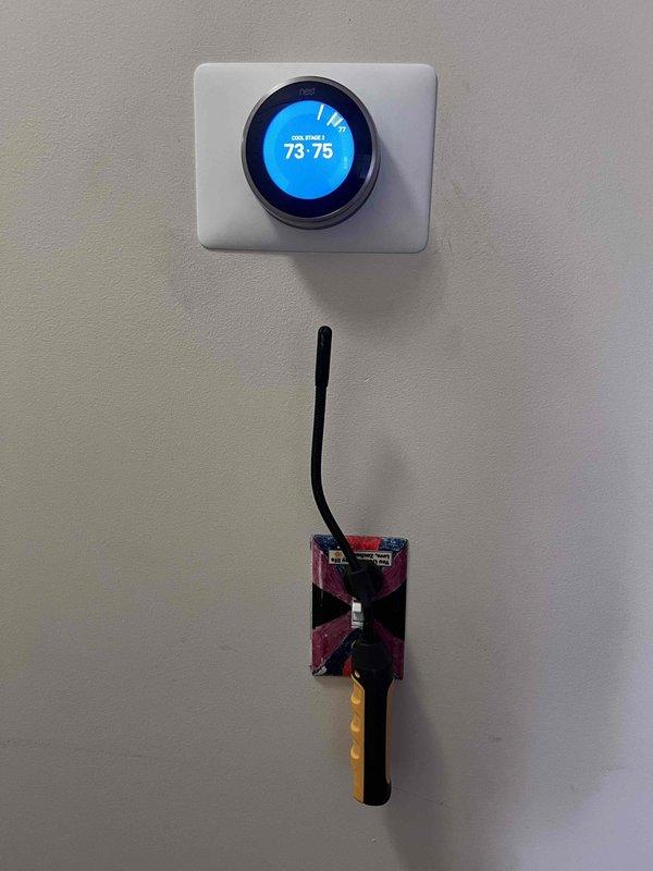 Responded to callback for reported heating operation when thermostat was set to 73–76°F. Inspected Nest thermostat base plate and verified wiring terminations at Y1, Y2, G, W1, C, and Rh, noting unterminated R and W conductors tucked in the wall cavity. Observed the thermostat displaying "COOL STAGE 2" and used a handheld inspection probe to check the wall surface for anomalies, finding no damage, frost, or rust. Documented wiring configuration and thermostat operating status for team review and coordination of next steps.
