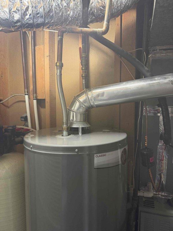 Responded to a no-hot-water complaint on a standard gas-fired tank water heater, 6+ years old, and inspected the unit, gas supply, venting, and water connections. No leaks, corrosion, or visible damage were found, and the flexible water connectors, angled exhaust vent, and gas piping were intact. The unit was evaluated for pilot light/ignition failure and proper operation was addressed to restore hot water.