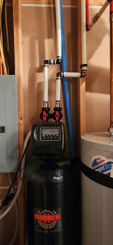 Installed a new Sentry II water softener with a digital control head in the utility room, connecting it to the home's plumbing with isolation/bypass valves and flexible supply lines. Routed the drain line to the existing floor drain, secured it with zip ties, and verified a clean installation with no visible leaks or damage.