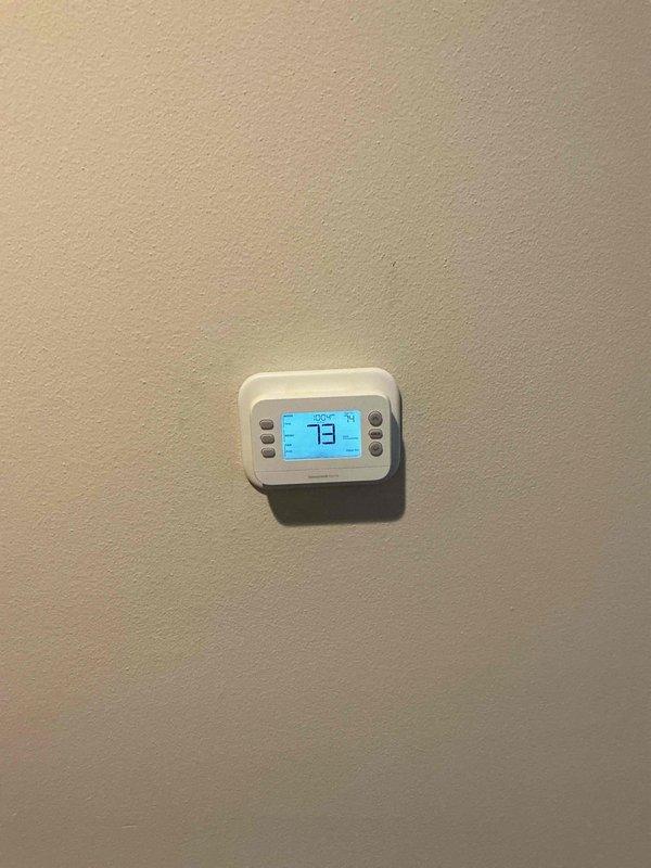 Completed no-charge installation of previously uninstalled thermostat. Mounted digital thermostat with blue backlit LCD display and verified proper operation with temperature reading at 73°F. No additional issues found.