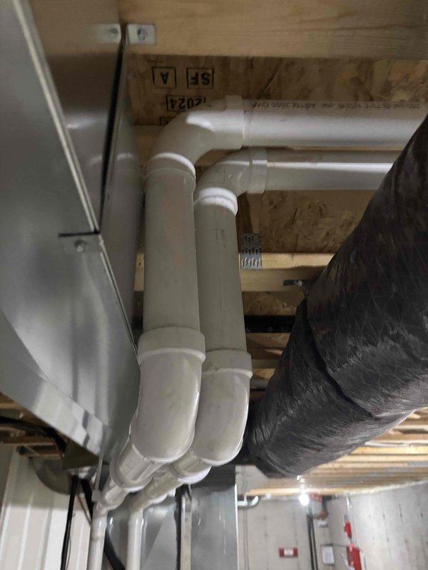 Inspected reported furnace vent leak in basement. Examined PVC venting system attached to ceiling joists, focusing on all elbows, joints, and connections. No active leaks detected in the exhaust venting during inspection. Visual assessment of nearby black insulated ductwork confirmed proper installation with no condensation issues.