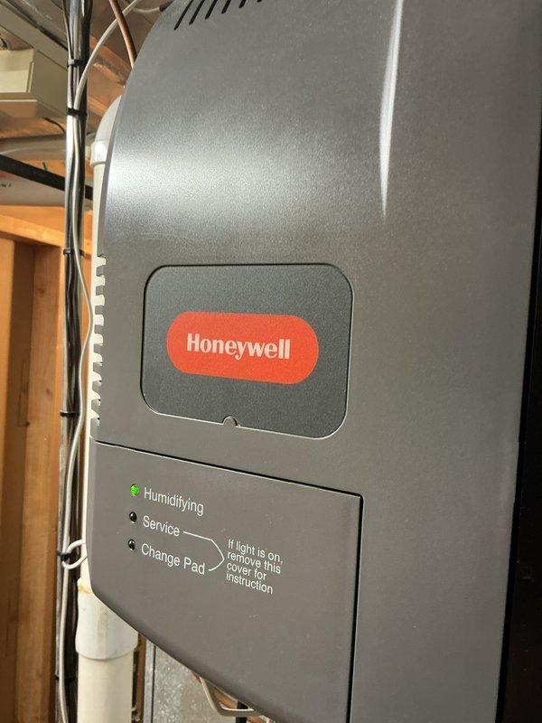 Responded to service call regarding Honeywell humidifier leaking onto floor. Diagnosed issue as plugged drain line. Successfully cleared blockage by blowing out the drain, restoring proper drainage function. Verified humidifier operation with green "Humidifying" indicator light confirming normal function post-repair.