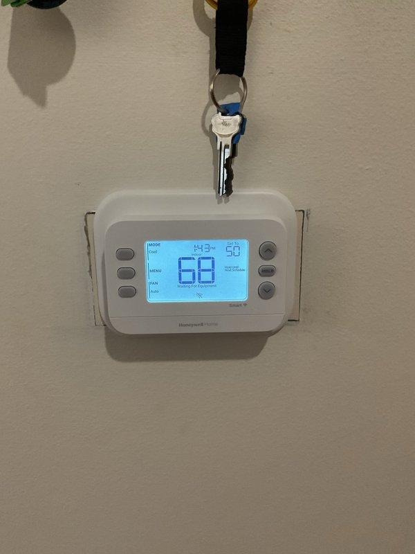 Completed thermostat replacement service, removing outdated unit and installing new Honeywell Home digital programmable thermostat. Connected and tested all wiring (green, red, white) to ensure proper functionality, with system now operating correctly showing 68° current temperature with 50° set point in HOME mode.