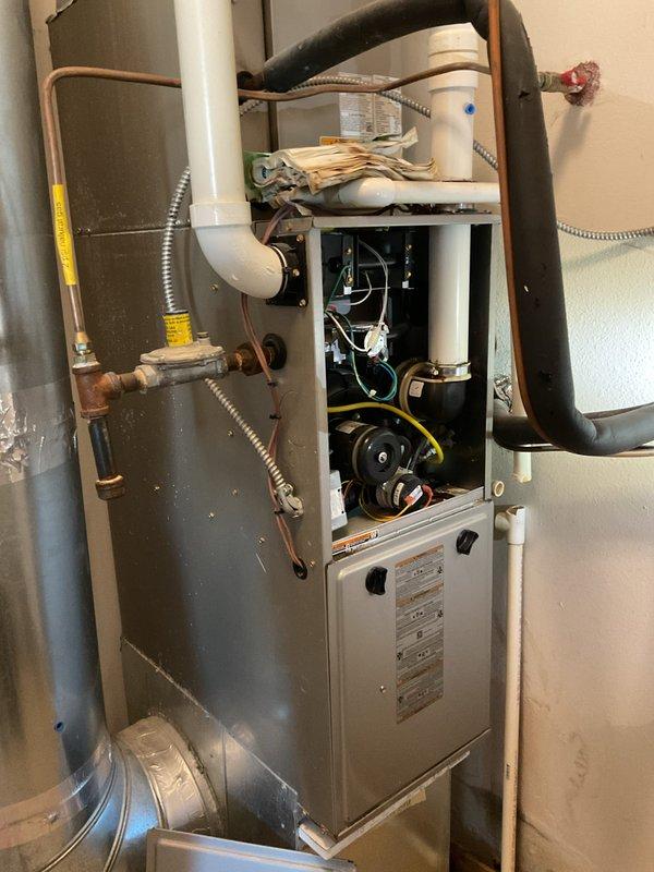 Responded to service call for water leakage from furnace. Upon inspection of the high-efficiency unit, diagnosed condensate drainage issue. Removed front panels to access internal components, cleaned blocked drain line, and verified proper drainage system function. System now operating normally with no leaks detected.