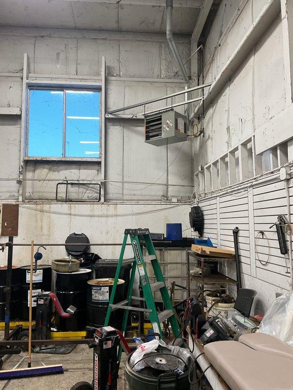 Diagnosed two non-operational heating units in industrial workspace. Inspected ceiling-mounted ventilation/heating system with louvers and wall-mounted heating unit with vents. Units require repair to restore proper heating function in this utility area.