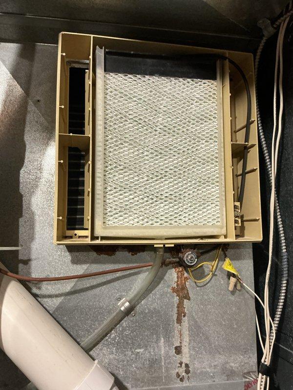 Responded to service call regarding detached Aprilaire humidifier. Inspection revealed the unit had fallen from mounting on furnace, causing damage to the housing and internal components. Observed significant rust/corrosion on the metal surface beneath the installation point. Recommended complete replacement of the humidifier rather than repair due to extent of damage and compromised mounting area.