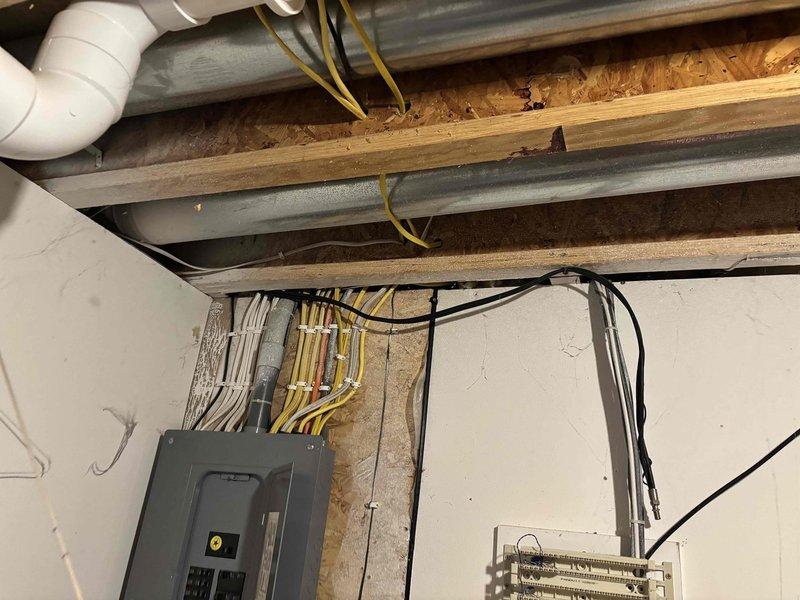 Conducted site assessment for potential A/C unit relocation. Evaluated current installation in unfinished basement/utility area, documenting existing infrastructure including electrical panel connections, plumbing interfaces, and structural considerations. Photos taken of exposed joists, conduits, and utility connections to develop comprehensive relocation estimate.