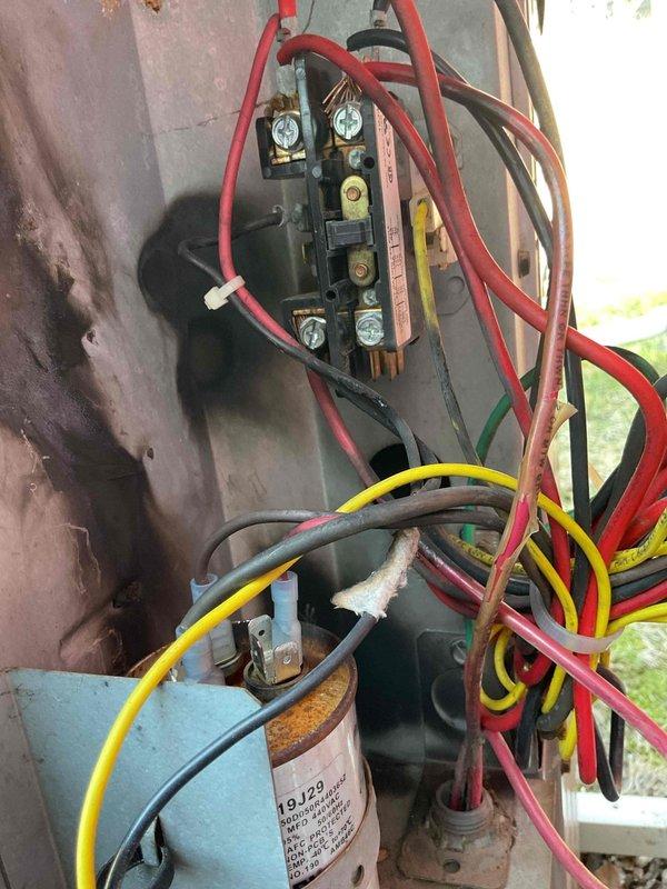 Responded to no cooling complaint on 6-9 year old central air conditioning system. Upon arrival, unit would not run. Diagnosed faulty hard start kit relay with evidence of electrical failure and blackened contactor. Bypassed relay to test system operation, which confirmed compressor mechanical failure indicated by excessive noise and grinding sounds consistent with internal connecting rod damage. Visual inspection revealed significant heat damage and carbon scoring on indoor electrical connections, along with weathered outdoor unit components. Previous service history indicated recurring refrigerant loss with no identified leak at evaporator coil. Based on diagnostic findings of failed compressor with suspected internal mechanical damage, combined with compromised electrical components showing thermal stress, system requires compressor replacement or full condensing unit replacement to restore cooling operation.
