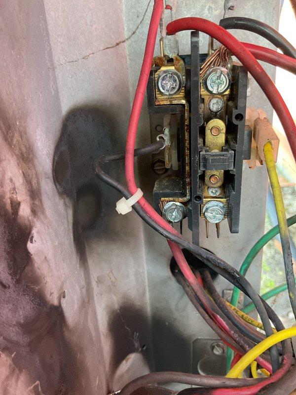 Responded to no cooling complaint on 6-9 year old central air conditioning system. Upon arrival, unit would not run. Diagnosed faulty hard start kit relay with evidence of electrical failure and blackened contactor. Bypassed relay to test system operation, which confirmed compressor mechanical failure indicated by excessive noise and grinding sounds consistent with internal connecting rod damage. Visual inspection revealed significant heat damage and carbon scoring on indoor electrical connections, along with weathered outdoor unit components. Previous service history indicated recurring refrigerant loss with no identified leak at evaporator coil. Based on diagnostic findings of failed compressor with suspected internal mechanical damage, combined with compromised electrical components showing thermal stress, system requires compressor replacement or full condensing unit replacement to restore cooling operation.