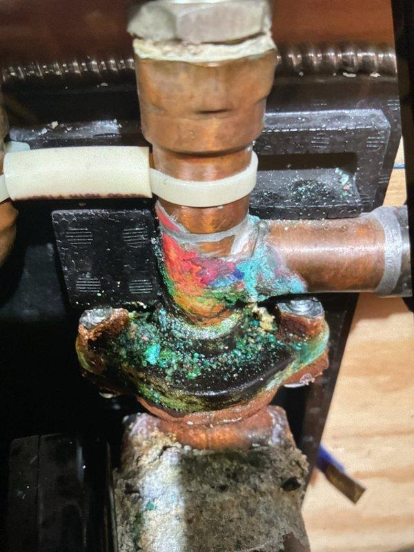 Performed comprehensive clean and check service on residential heating system, air conditioning unit, and boiler. Furnace and air conditioner inspected and found operating within normal parameters with no issues detected. Boiler inspection revealed active leak at manifold pipe connection with significant corrosion, mineral buildup, and oxidation present throughout copper piping and fittings. Circulation pump assembly showing advanced deterioration with white scale deposits and green patina on copper components. Recommended replacement of corroded manifold pipe, boiler sensor, and exhaust port to restore proper system operation and prevent further damage.