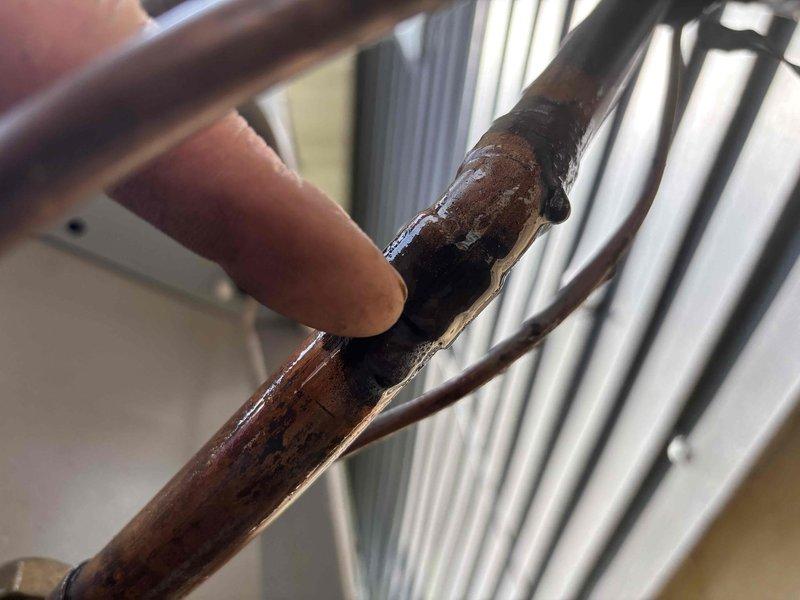 Responded to service call for air conditioning unit with reported refrigerant leak. Upon inspection, identified severe corrosion and deterioration on copper refrigerant line at connection joint near condenser unit. Corrosion exhibited dark discoloration, surface pitting, and compromised pipe integrity at affected junction point. Documented damage with photographs showing extent of copper line degradation. Provided customer with quote for repair, as unit warranty covers equipment only and does not include labor costs for leak repair.
