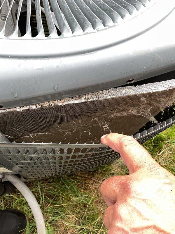 Responded to no cooling complaint on residential air conditioning system. Upon inspection, found outdoor condensing unit with heavily contaminated condenser coil and protective screening covered with dirt, debris, and organic matter restricting airflow. Indoor system equipped with severely restricted air filter impeding proper system operation.

Performed thorough condenser coil cleaning by rinsing down exterior unit to restore adequate airflow through heat exchanger. Replaced restrictive air filter with new filter provided by homeowner. Replaced thermostat batteries to ensure proper system control and operation. System tested and confirmed returning to normal cooling operation following cleaning and maintenance procedures.