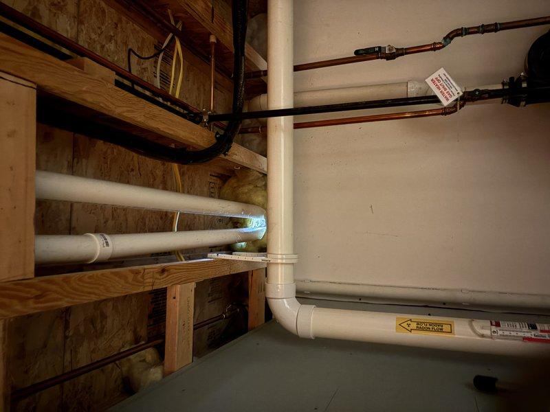 Responded to callback for air conditioning system that was relocated in March. Upon inspection, discovered inadequate sealing around refrigerant line penetrations through basement wall, allowing visible daylight and air infiltration. Properly sealed all pipe penetrations where copper refrigerant lines pass through the foundation wall using appropriate weatherproofing materials to prevent air leakage and maintain building envelope integrity. Verified all seals were complete and inspected exterior PVC condensate drain routing on roofline to ensure proper drainage function.