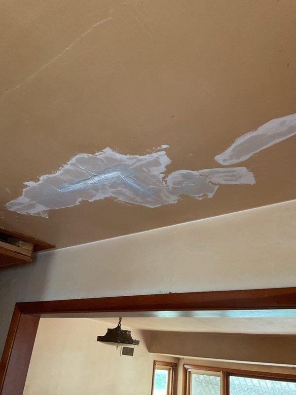 Responded to service call for damaged ceiling plaster in kitchen area. Accessed attic space and reinforced structural support by tying the existing kitchen ceiling joists into crossmember framing to prevent future sagging and cracking. Performed drywall and plaster repair on ceiling, applying joint compound and mesh tape to damaged areas. Completed similar repair work on adjacent wall section where drywall damage was present, installing mesh tape and applying multiple coats of joint compound to ensure proper adhesion and structural integrity.