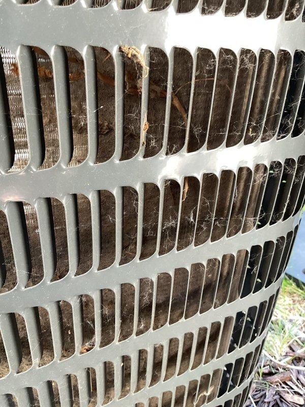 Responded to no cooling complaint on residential air conditioning system. Upon arrival, found outdoor condenser unit with heavily soiled coil fins containing significant accumulation of dirt, dust, debris, and organic matter lodged between fins. Performed exterior coil cleaning by rinsing unit to remove buildup and restore proper airflow. After cleaning and attempting startup, diagnosed failed hermetic compressor capacitor preventing unit operation. Contacted customer for authorization to proceed with repair. Replaced defective capacitor with new component. Conducted operational testing following repair. Verified compressor startup, confirmed proper system operation, and validated cooling performance. Customer reported fresh filter already installed at furnace. Unit restored to normal cooling operation.