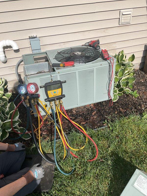 Responded to no cooling complaint on 22-year-old system. Upon inspection, found unit low on R-22 refrigerant with insufficient system pressures for proper operation. Performed clean and check service on outdoor condensing unit, including inspection of electrical components and connections. Connected manifold gauge set and confirmed refrigerant charge was significantly below manufacturer specifications. Customer also reported intermittent operation issues and blower motor concerns on furnace, which showed signs of age-related strain. System pressures remained inadequate after cleaning despite service attempts, indicating substantial refrigerant loss requiring further evaluation and repair to restore cooling capacity.